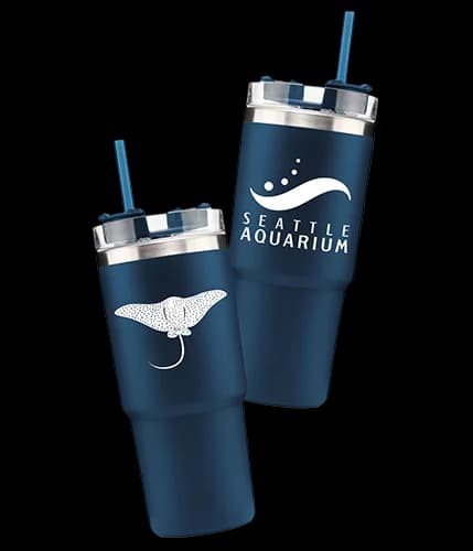 Seattle Aquarium drink tumblers with an illustration of a ray and the Aquarium logo on different sides of the tumbler.